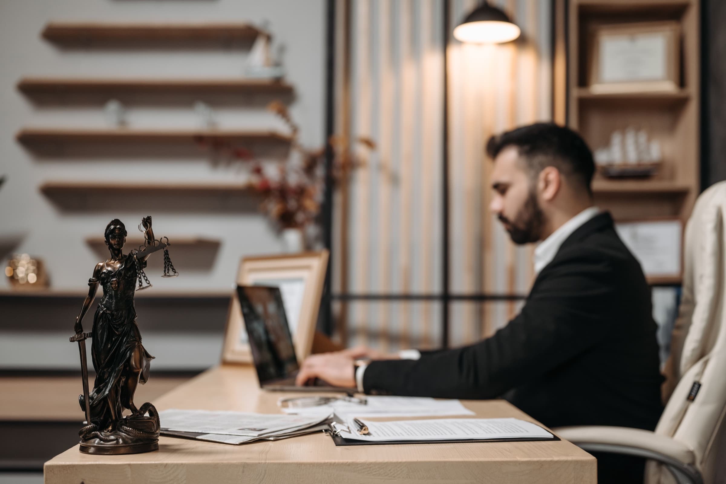 Attorney working at a laptop in a law office with a Lady Justice statue in the foreground